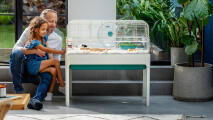 Father and daughter watching their hamster in a sleek design hamster cage