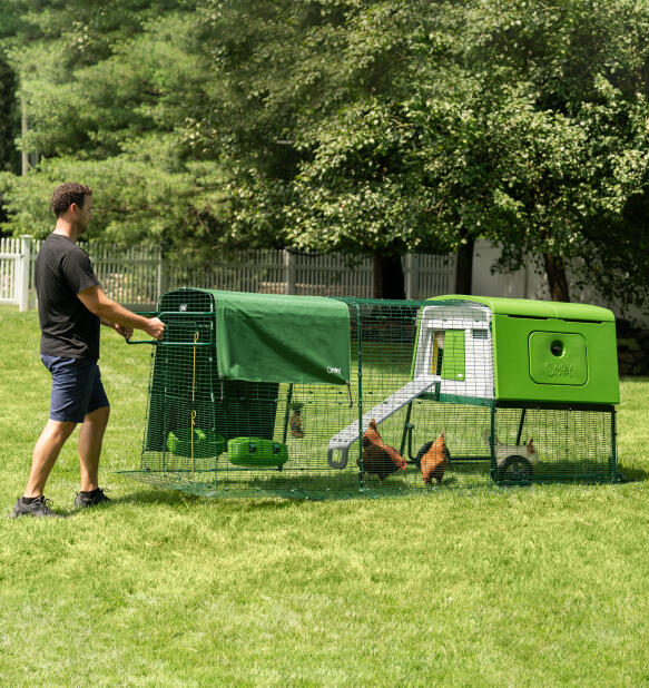 Man moving the Eglu Cube portable chicken coop with wheels and handles