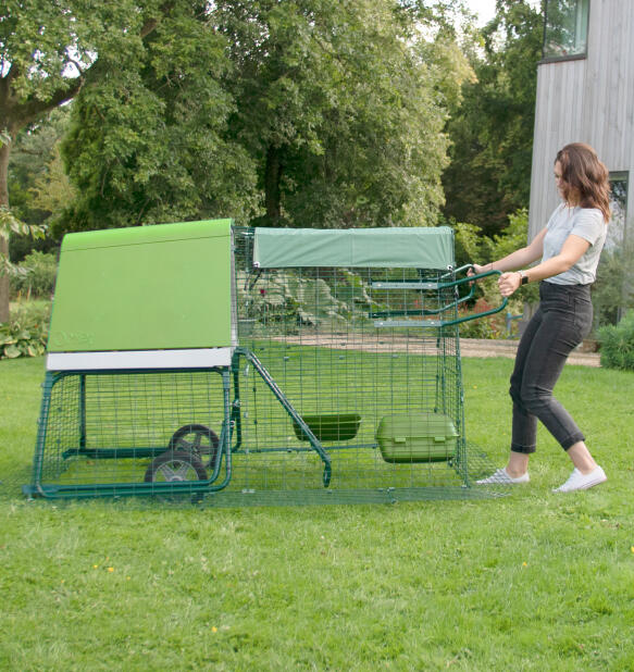 Woman moving the Eglu Go portable chicken coop in her backyard